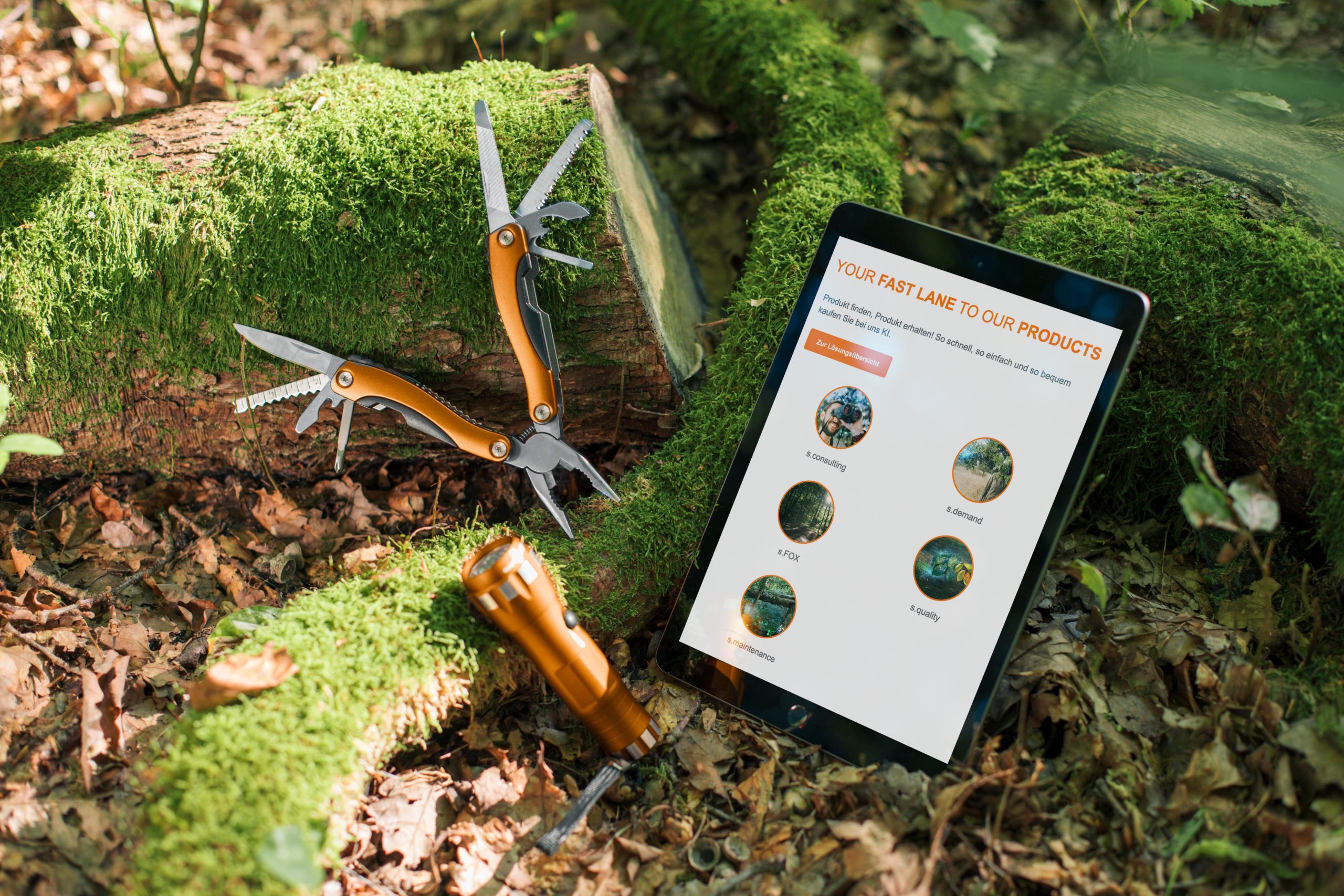 Tablet, Taschenlampe und Multifunktionswerkzeug liegen im Moss im Wald. Auf dem Tabletbildschirm sind die verschiedenen statmath Produkte zu sehen.